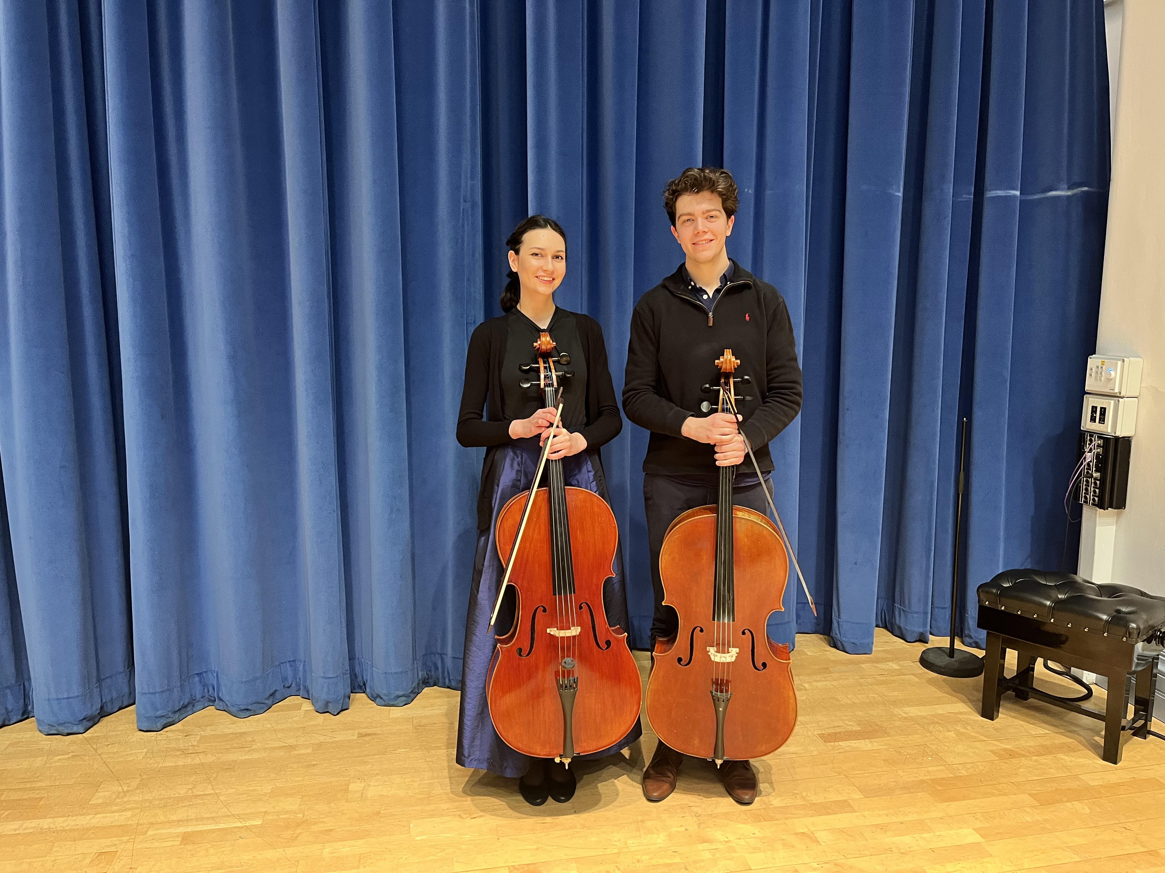 A photo of both Mina Jachimowicz (MA Music Historical Performance) and Nick Booth (BA Music) standing behind thier Cellos